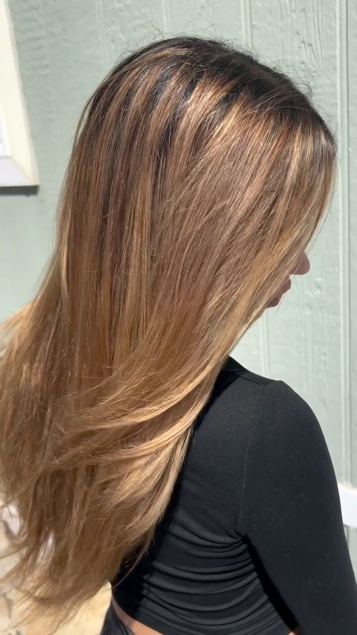 Long layered hair with warm honey and caramel balayage, side profile